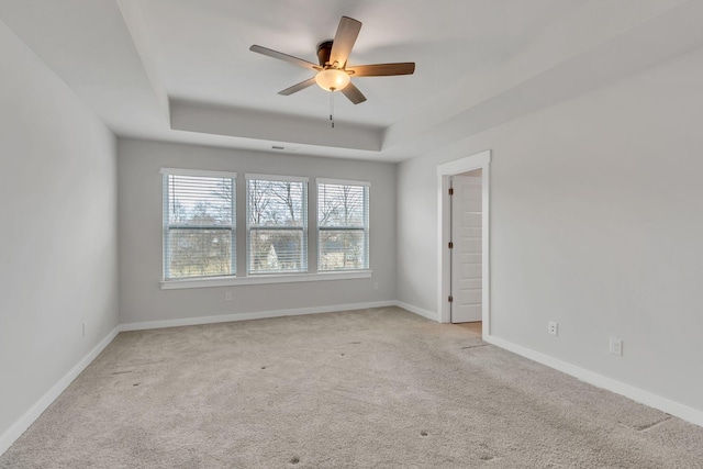 spare room with light colored carpet, a raised ceiling, and ceiling fan