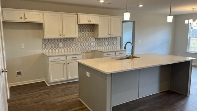 kitchen featuring white cabinetry, an island with sink, and hanging light fixtures