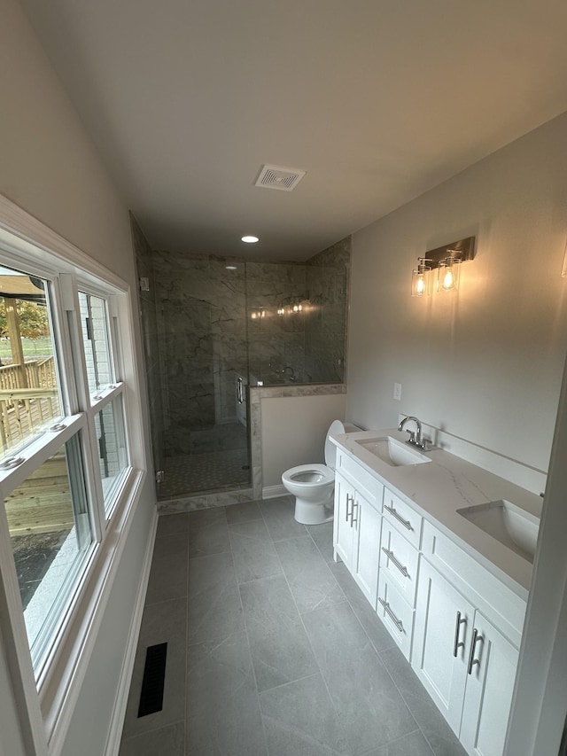 bathroom featuring tile patterned flooring, vanity, a shower with shower door, and toilet