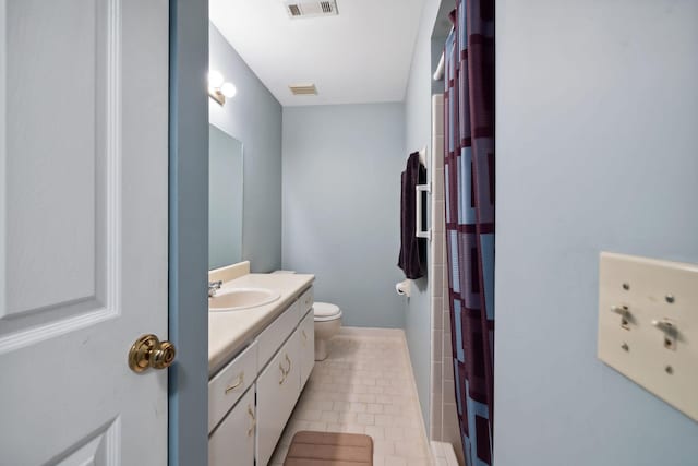 bathroom featuring tile patterned flooring, vanity, toilet, and curtained shower