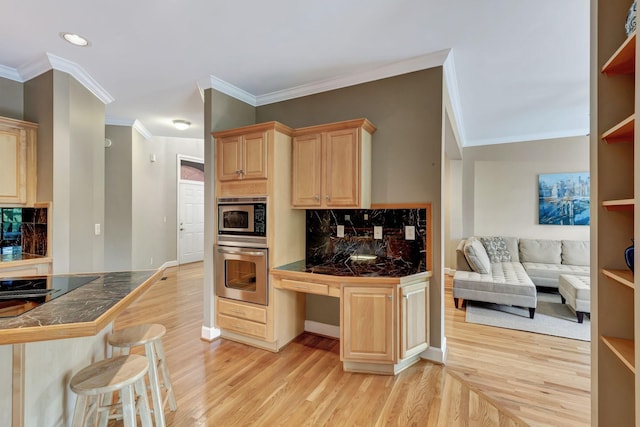 kitchen featuring tile countertops, crown molding, light brown cabinetry, a kitchen bar, and stainless steel appliances