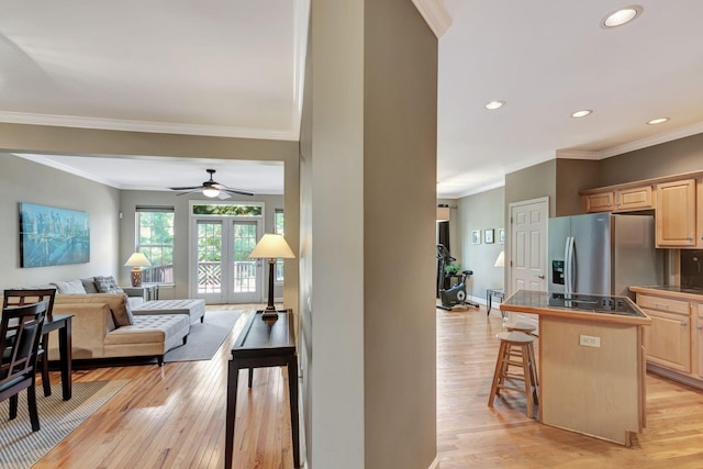 kitchen featuring appliances with stainless steel finishes, light wood-type flooring, light brown cabinets, a center island, and a breakfast bar area