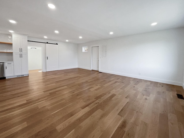 unfurnished living room featuring a barn door and light wood-type flooring