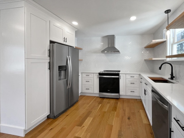 kitchen with wall chimney range hood, sink, appliances with stainless steel finishes, tasteful backsplash, and white cabinetry