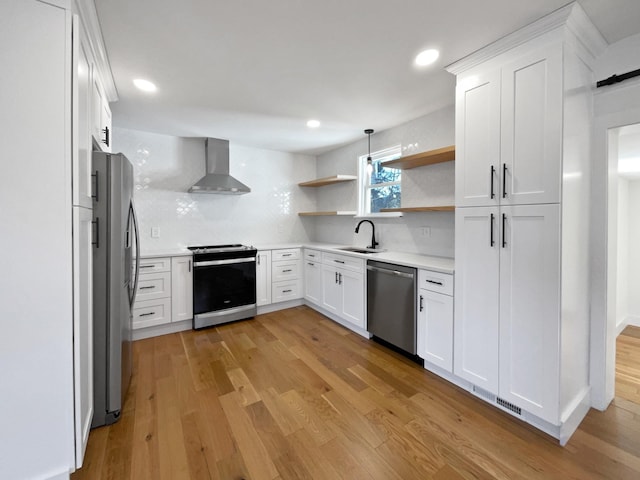 kitchen featuring sink, wall chimney range hood, backsplash, white cabinets, and appliances with stainless steel finishes