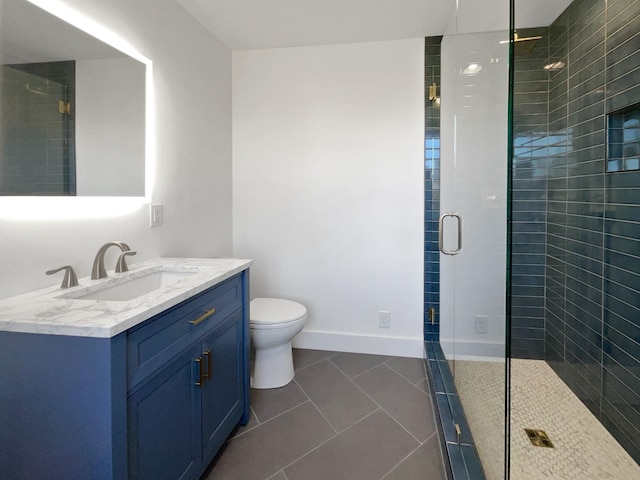 bathroom featuring tile patterned flooring, vanity, a shower with shower door, and toilet