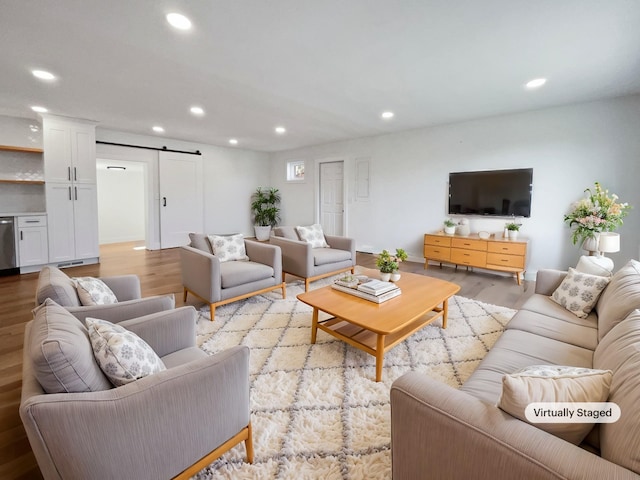 living room with a barn door and light wood-type flooring