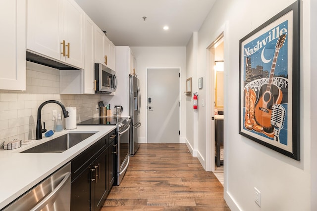 kitchen featuring tasteful backsplash, stainless steel appliances, sink, light hardwood / wood-style flooring, and white cabinets