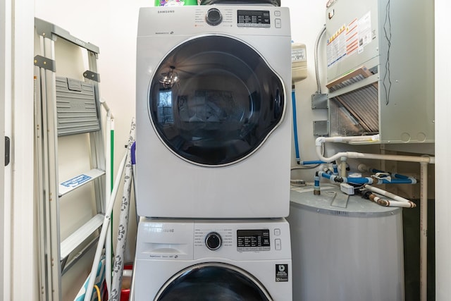 clothes washing area with stacked washer / drying machine and water heater