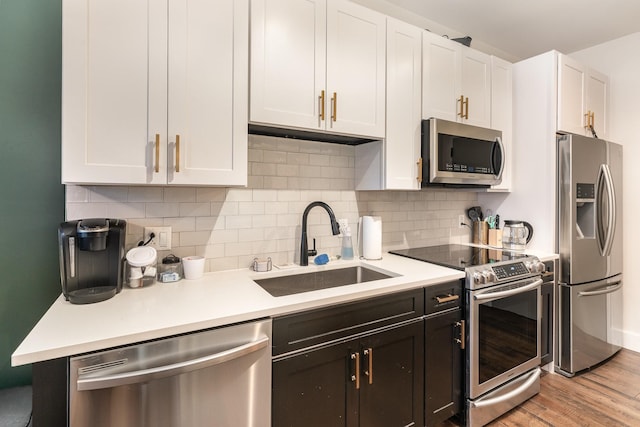 kitchen featuring backsplash, white cabinets, sink, light hardwood / wood-style flooring, and stainless steel appliances