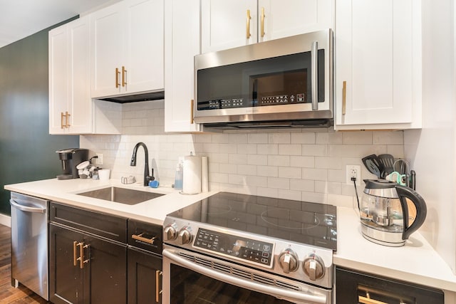 kitchen featuring decorative backsplash, sink, white cabinetry, and stainless steel appliances