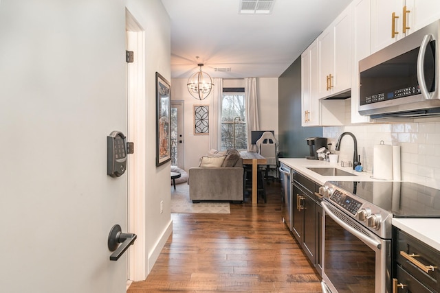 kitchen featuring sink, hanging light fixtures, stainless steel appliances, dark hardwood / wood-style floors, and white cabinets