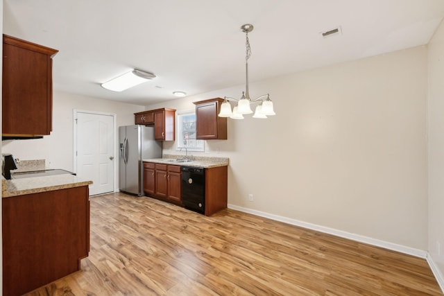 kitchen featuring sink, stainless steel fridge, stove, black dishwasher, and decorative light fixtures