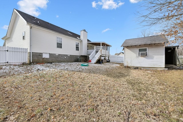 rear view of house with cooling unit, central AC unit, and a yard