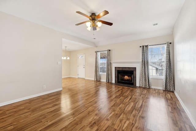 unfurnished living room with ceiling fan with notable chandelier, hardwood / wood-style floors, and a wealth of natural light