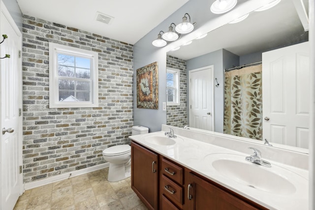 bathroom featuring vanity, brick wall, and toilet