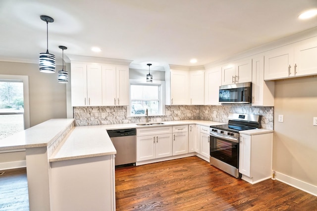 kitchen with pendant lighting, kitchen peninsula, sink, appliances with stainless steel finishes, and white cabinetry