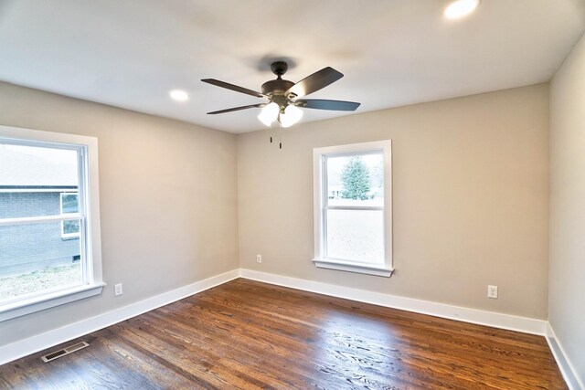 spare room with ceiling fan, a healthy amount of sunlight, and dark wood-type flooring