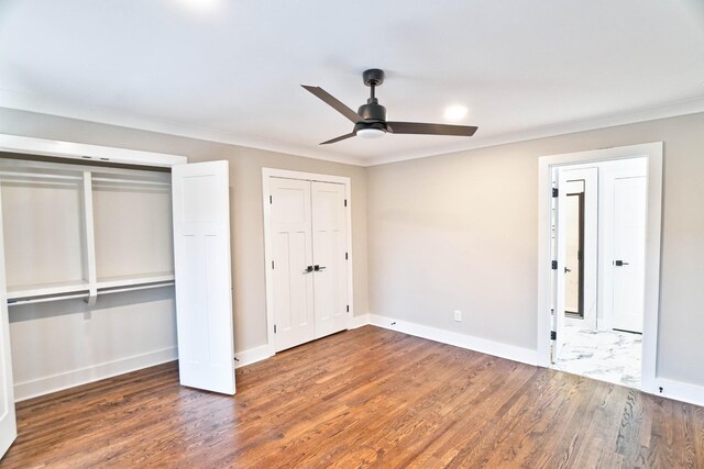 unfurnished bedroom featuring multiple closets, ceiling fan, crown molding, and dark hardwood / wood-style floors