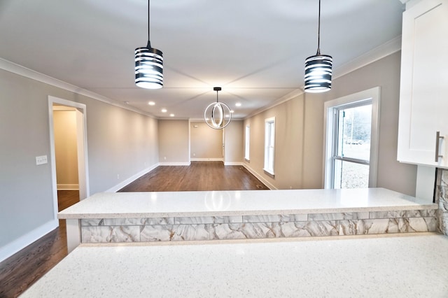 kitchen featuring light stone countertops, dark hardwood / wood-style flooring, ornamental molding, pendant lighting, and a notable chandelier