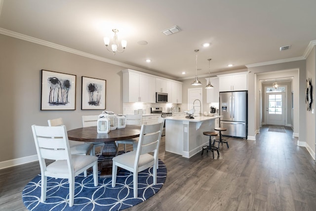 dining room featuring a chandelier, ornamental molding, dark wood-type flooring, and sink