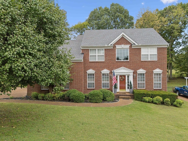 colonial-style house featuring a front lawn