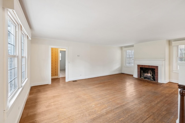 unfurnished living room with light wood-type flooring and a brick fireplace