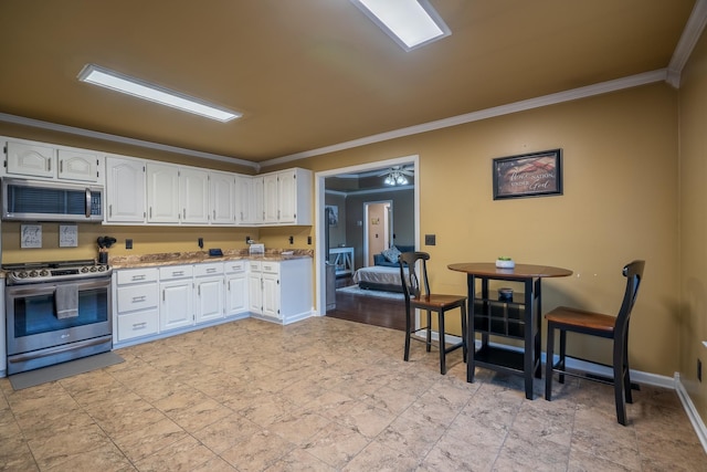 kitchen featuring stainless steel appliances, light stone counters, white cabinetry, and crown molding