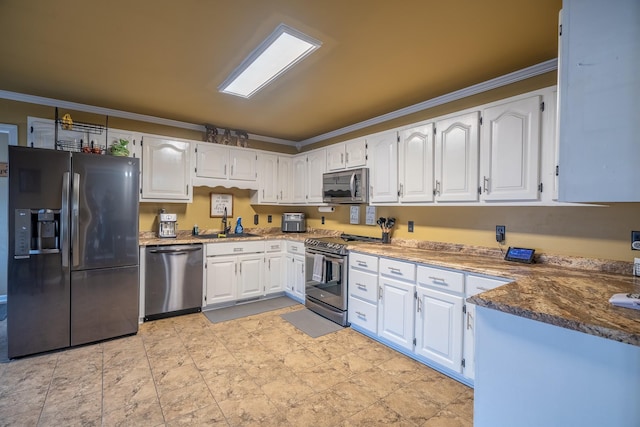 kitchen with dark stone countertops, white cabinetry, ornamental molding, and appliances with stainless steel finishes