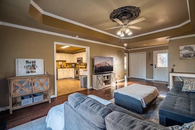 living room featuring hardwood / wood-style floors, ceiling fan, a raised ceiling, and ornamental molding