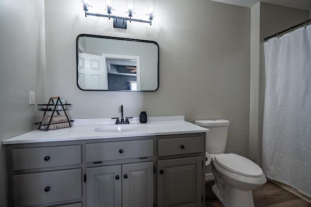 bathroom with hardwood / wood-style flooring, vanity, curtained shower, and toilet