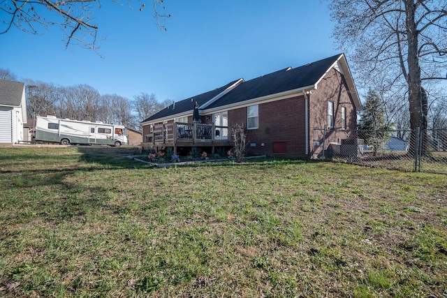 rear view of property featuring a lawn and a deck