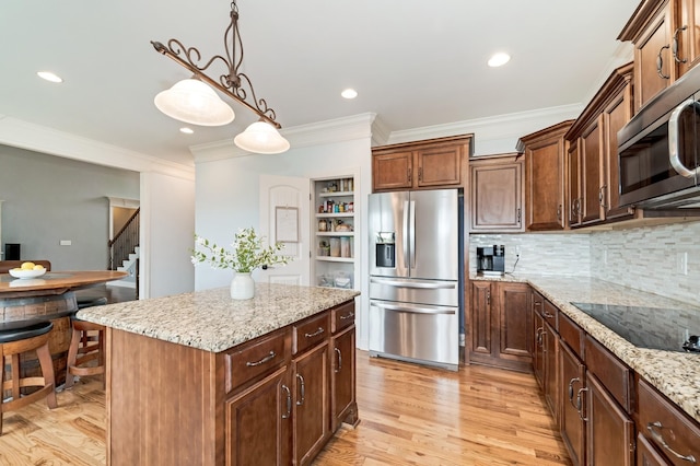 kitchen with light stone countertops, appliances with stainless steel finishes, crown molding, a center island, and hanging light fixtures