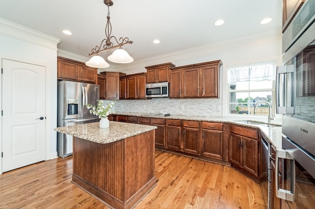 kitchen featuring backsplash, stainless steel appliances, sink, pendant lighting, and a kitchen island