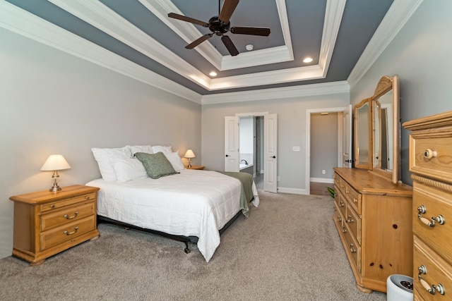 carpeted bedroom with a tray ceiling, ensuite bath, ceiling fan, and ornamental molding