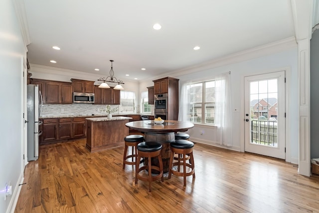 kitchen with light stone countertops, a center island, pendant lighting, a breakfast bar area, and appliances with stainless steel finishes