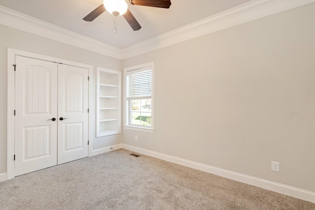 unfurnished bedroom with carpet, a closet, ceiling fan, and crown molding