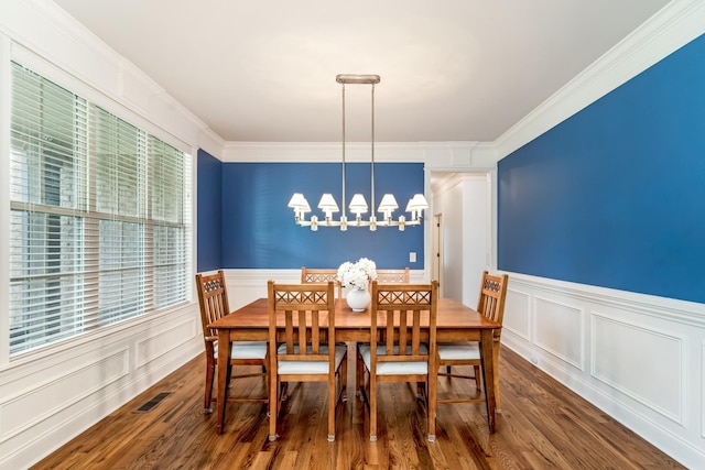 dining room with dark hardwood / wood-style flooring, crown molding, and a chandelier