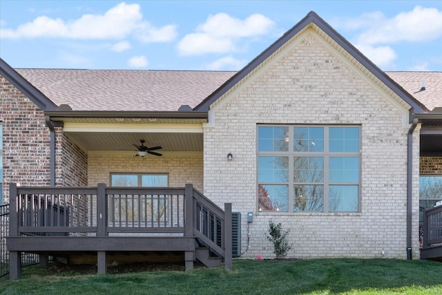 back of property featuring ceiling fan, a wooden deck, and a lawn