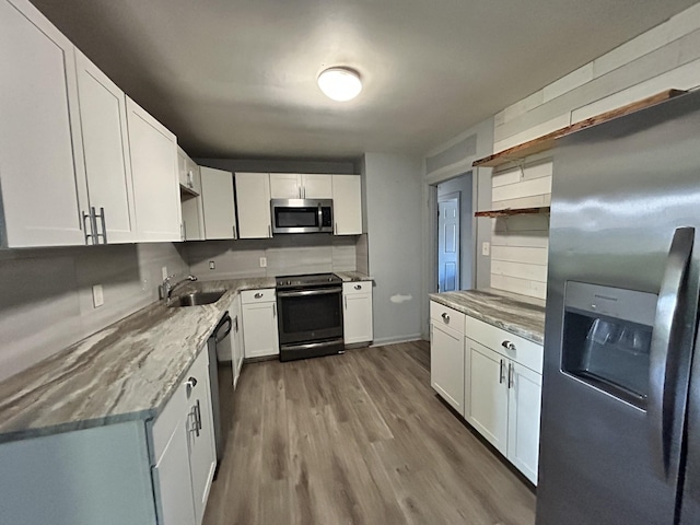 kitchen with hardwood / wood-style floors, sink, decorative backsplash, white cabinetry, and stainless steel appliances