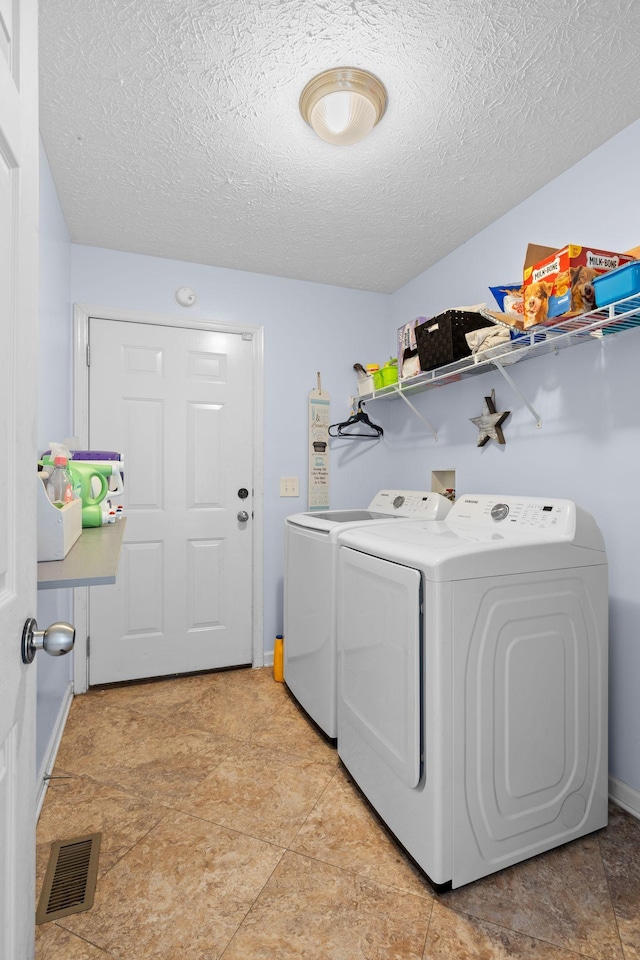 laundry room with washing machine and dryer and a textured ceiling