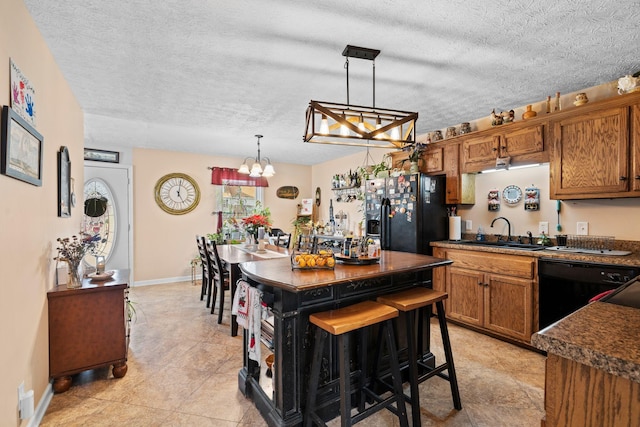 kitchen featuring sink, a breakfast bar area, a center island, pendant lighting, and black appliances