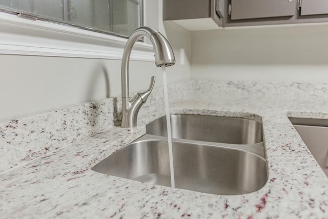 interior details featuring light stone countertops and sink