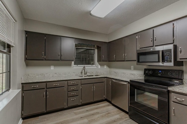 kitchen featuring sink, stainless steel appliances, a textured ceiling, and light wood-type flooring