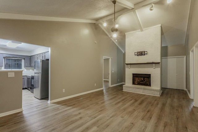 unfurnished living room featuring a fireplace, wood-type flooring, a textured ceiling, and high vaulted ceiling