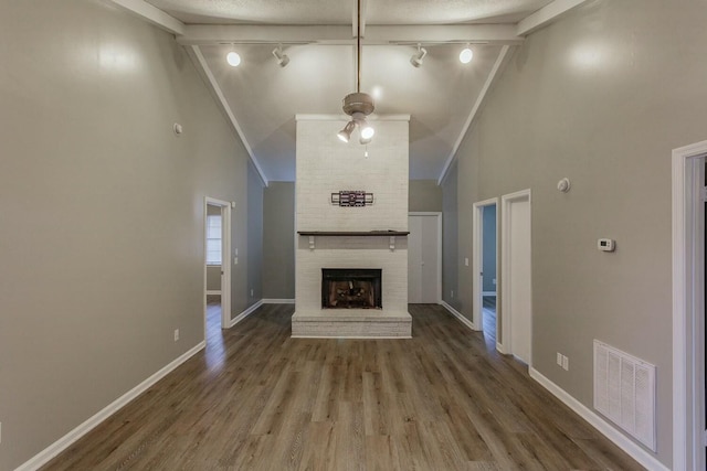 unfurnished living room with rail lighting, wood-type flooring, a fireplace, and high vaulted ceiling