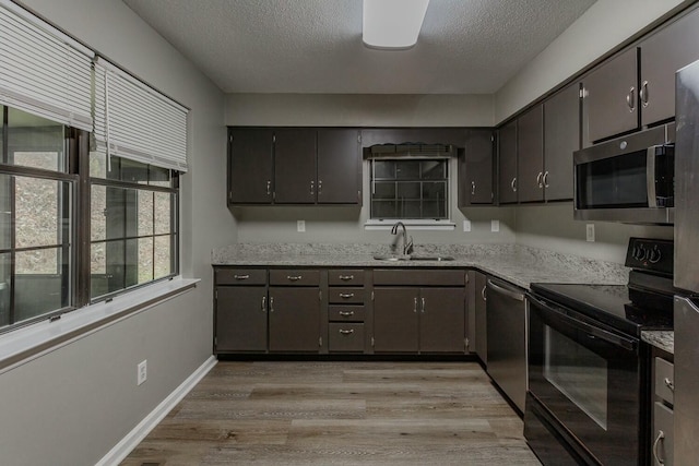 kitchen featuring light wood-type flooring, appliances with stainless steel finishes, a textured ceiling, and sink