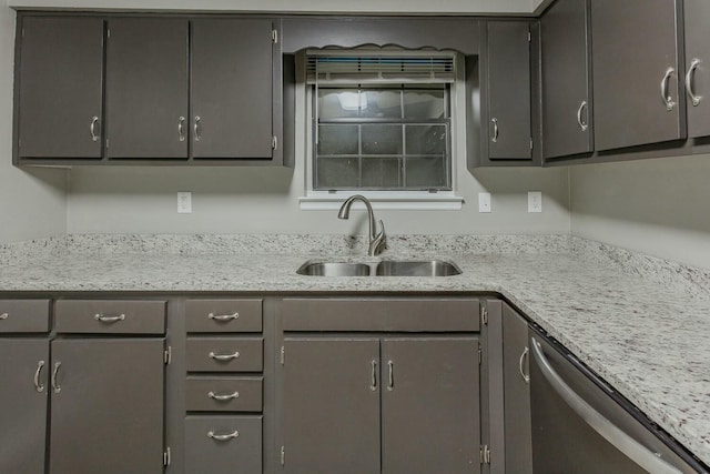 kitchen with stainless steel dishwasher, gray cabinets, light stone counters, and sink