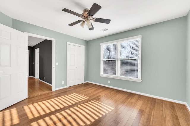 unfurnished bedroom with a closet, hardwood / wood-style flooring, and ceiling fan