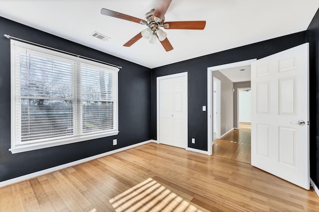 unfurnished bedroom featuring ceiling fan, wood-type flooring, and a closet